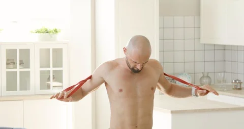 Man is doing exercise on his shoulders using elastic band in kitchen at home. Stock Footage 130160242