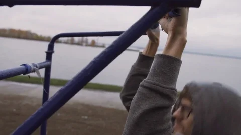 A man is doing an exercise on a horizontal bar in the street Stock Footage 82425773