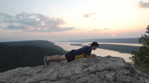 Man doing exercise at the press on top of the mountain Stock Footage 68595379