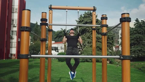 Man doing exercise on rings outdoors Video stock 254031334