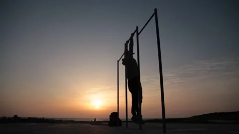 Man doing exercises on the crossbar against sunset background. Workout. Stock Footage 170755792