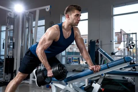 Man doing exercises with one dumbbell in the gym Stock Photos