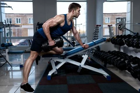 Man doing exercises with one dumbbell in the gym Stock Photos