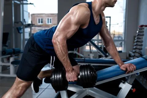 Man doing exercises with one dumbbell in the gym close-up Stock Photos