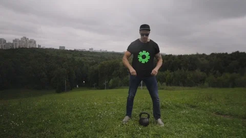 A man doing exercises with a weight on a hill overlooking the city. 120 FPS slow Stock Footage 93026677