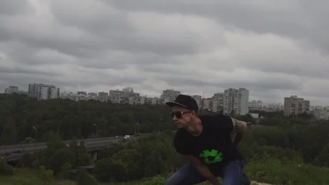 A man doing exercises with a weight on a hill overlooking the city. 60 FPS slow Stock Footage 93026811