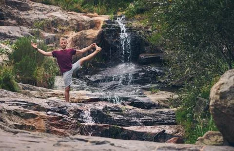 Man doing the extended standing hand to toe pose outdoors Stock Photos
