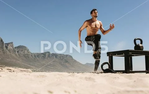 Man doing fitness training at the beach with kettlebells Stock Photos