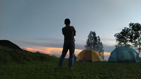 Man doing funny silly dance at family fun camping at bromo mountain forest conse Stock Footage 151299404