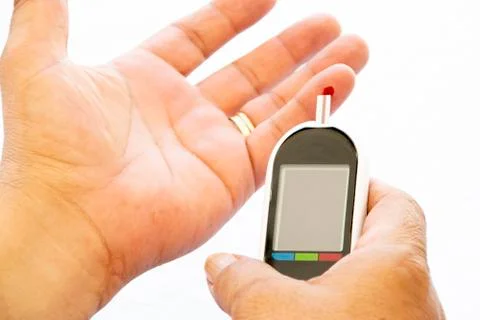 Man doing glucose test with a drop of blood on a diabetes device on a white b Stock Photos