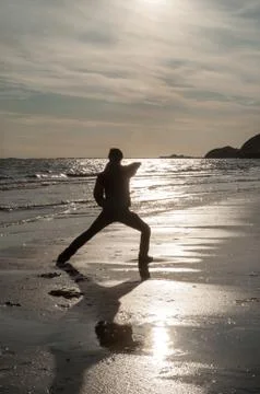 A man doing a hand strike at the beach at sunrise Stock Photos
