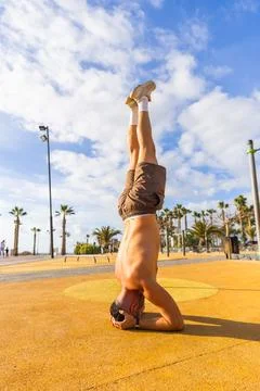 A man is doing a headstand on a yellow surface, yoga and meditation concept Stock Photos