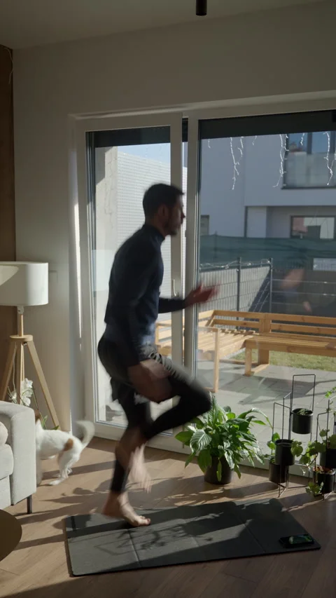 Man doing high knees exercise on mat at home in sunny living room Stock Footage 331253089