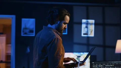 Man doing IT support job from home, walking around personal office with laptop 库存照片