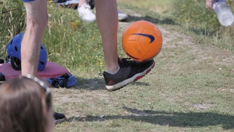 Man doing kick ups with orange football Vídeo Stock 221081427