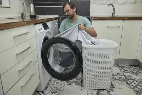 Man doing laundry at home in modern kitchen Stock Photos
