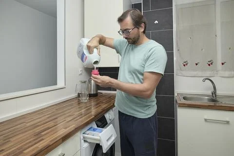 Man doing laundry at home in modern kitchen Stock Photos