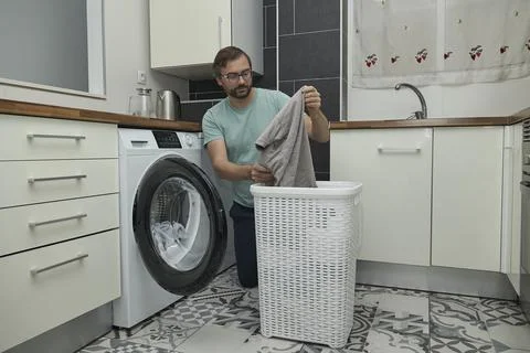 Man doing laundry at home in modern kitchen Stock Photos