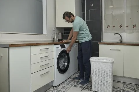 Man doing laundry at home in modern kitchen Stock Photos