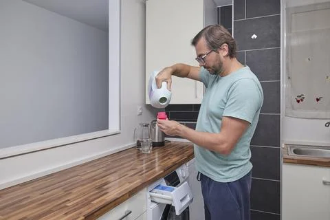 Man doing laundry at home in modern kitchen Stock Photos