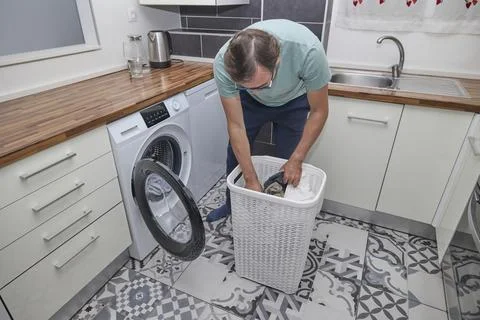 Man doing laundry at home in modern kitchen Stock Photos