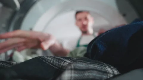 Man doing laundry inside washing machine with clothes piled up in drum during Stock Footage 305280738