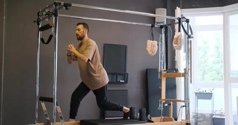 Man doing leg exercises on Pilates equipment Stock Footage 305783973