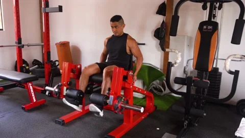 A man doing a leg extension exercise with both feet on a red machine Stock Footage 146500723