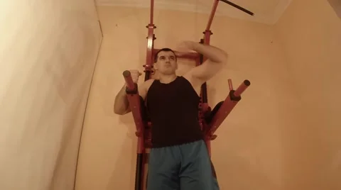 Man Doing Leg Lifts on Bars on Wall Bars in Room Stock Footage 62475385