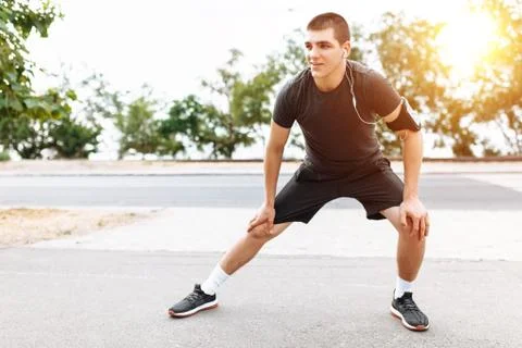 A man doing a leg stretch before Jogging, morning training, listening to musi Stock Photos