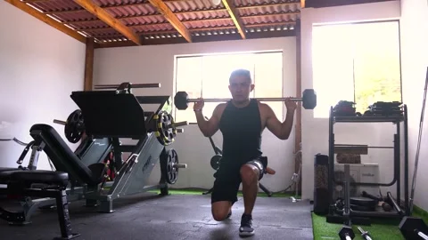 A man doing a lunge exercise by walking with a loaded bar on his back Stock Footage 146502099