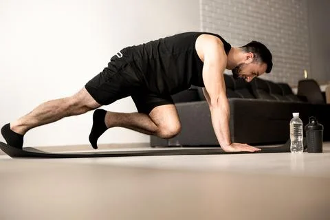 Man doing mountain climber exercises on black yoga mat. Morning workout. White Stock Photos