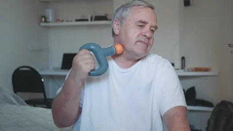 Man doing neck massage to himself with percussive vibrating massage gun Stock Footage 270683724