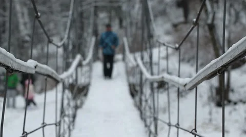 Man doing Norwegian walking along the suspension bridge over the river at winter Stock Footage 47546829