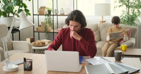 Man doing office work while son is using digital tablet in the background at Stock Footage 145219664