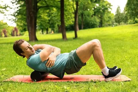 Man doing outdoor foam roller massage in a park. This myofascial release ex.. Fotos Stock