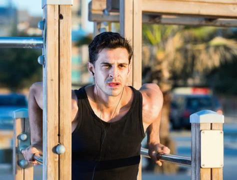 Man doing parallel bar dips to music on sports ground Stock-Fotos