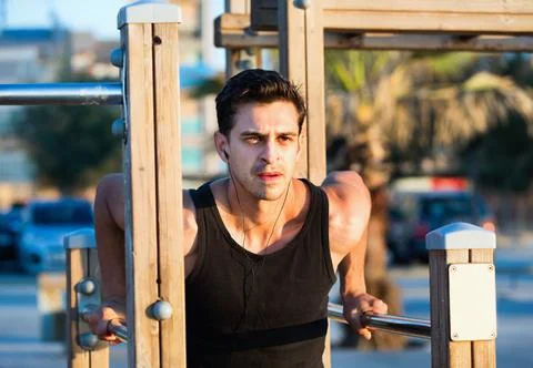Man doing parallel bar dips to music on sports ground Stock-Fotos