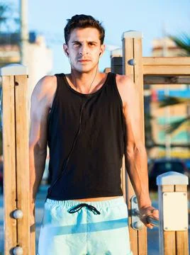 Man doing parallel bar dips to music on sports ground Stock Photos