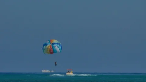 A man doing parasailing hunged on a multicolor parachute. Stock Footage 115424228