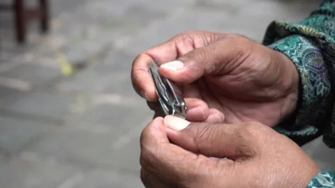 A man doing personal hygiene cutting his fingernails in the park Vídeos de archivo 227457601