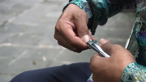 A man doing personal hygiene cutting his fingernails in the park 스톡 동영상 227457695