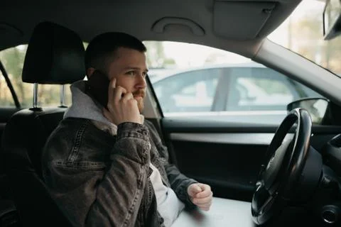 A man doing phone calls inside a comfort car, a laptop computer lies on his l Stock Photos