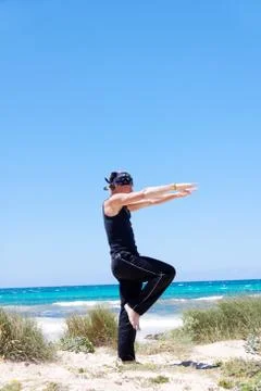 Man doing pilates exercises on beach in summer Stock Photos