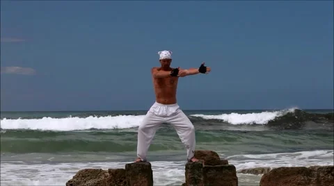 Man doing pilates on rocks in ocean II Stock Footage 41708856
