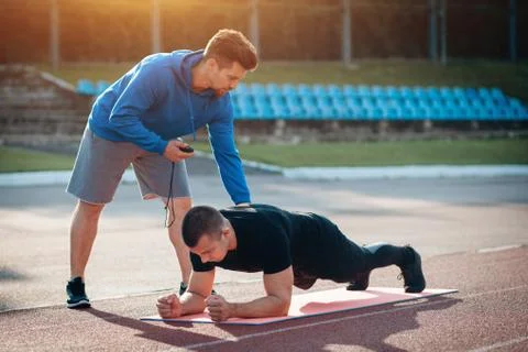 Man doing plank exercise and workout with personal fitness trainer outdoor Stock Photos