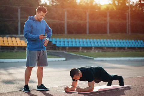 Man doing plank exercise and workout with personal fitness trainer outdoor Stock Photos