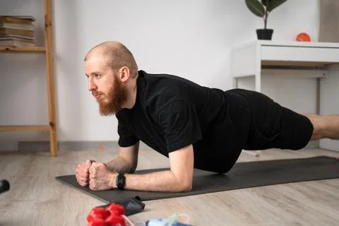 A man is doing plank exercises at home to improve fitness, focusing on his .. Stock Photos