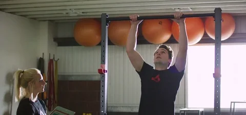 Man doing pull-up with his trainer at fitness studio 動画素材 77329554