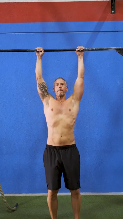 Man doing pull ups on bar in cross fit training gym. Stock Footage 253984091